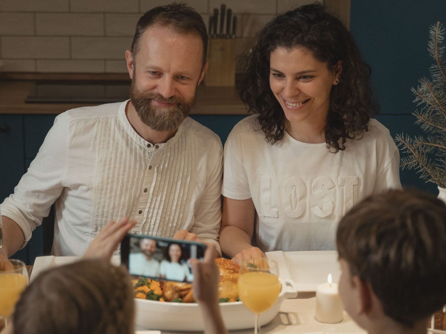 A family gathered around a holiday dinner table, smiling as one of the children takes a photo